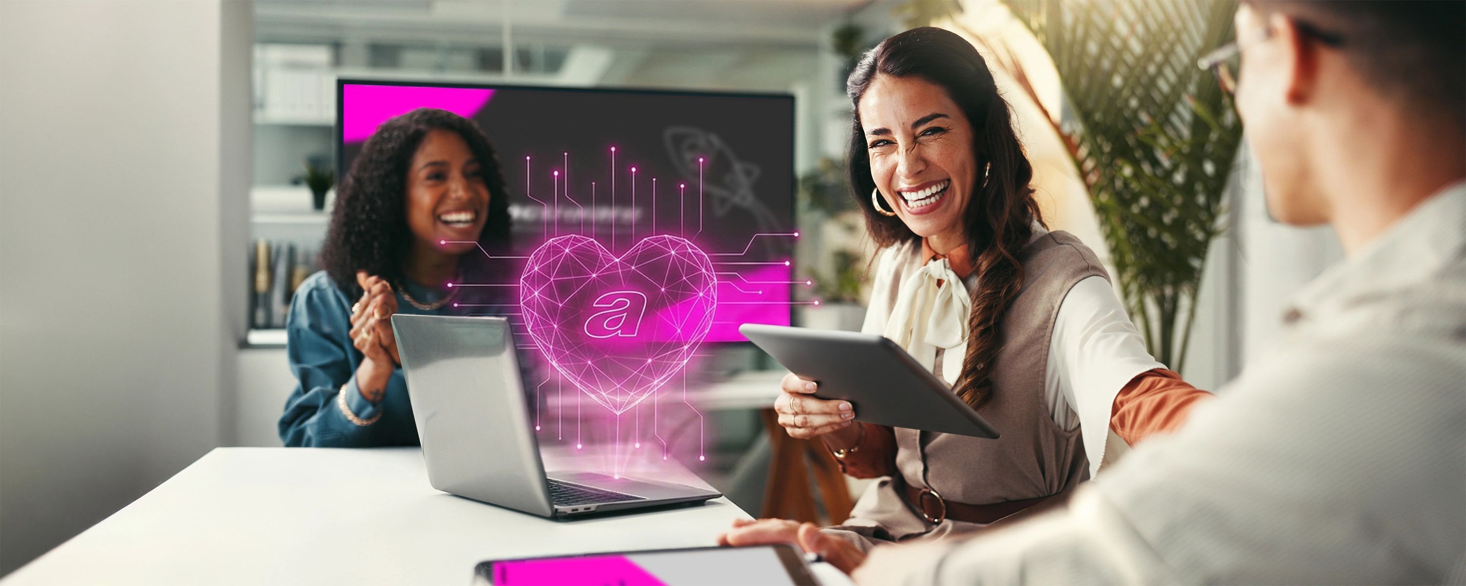 Drei lächelnde Kolleg*innen in modernem Büro bei einer Teambesprechung mit einem Laptop, auf dem ein digitales Herz und Datenvisualisierungen angezeigt werden.