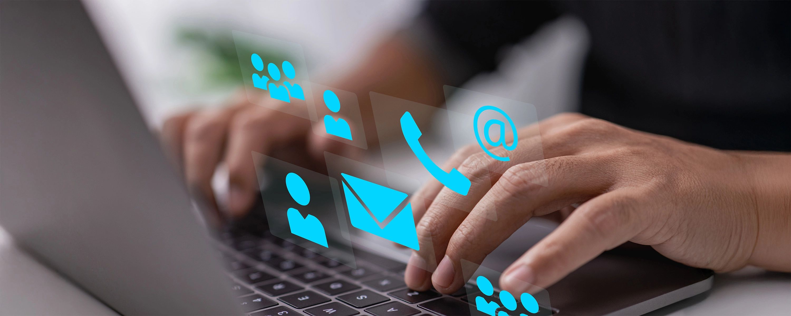 Person tippt auf Laptop-Tastatur, während digitale Symbole für E-Mail, Telefon, Kontakt und Kommunikation leuchten.
