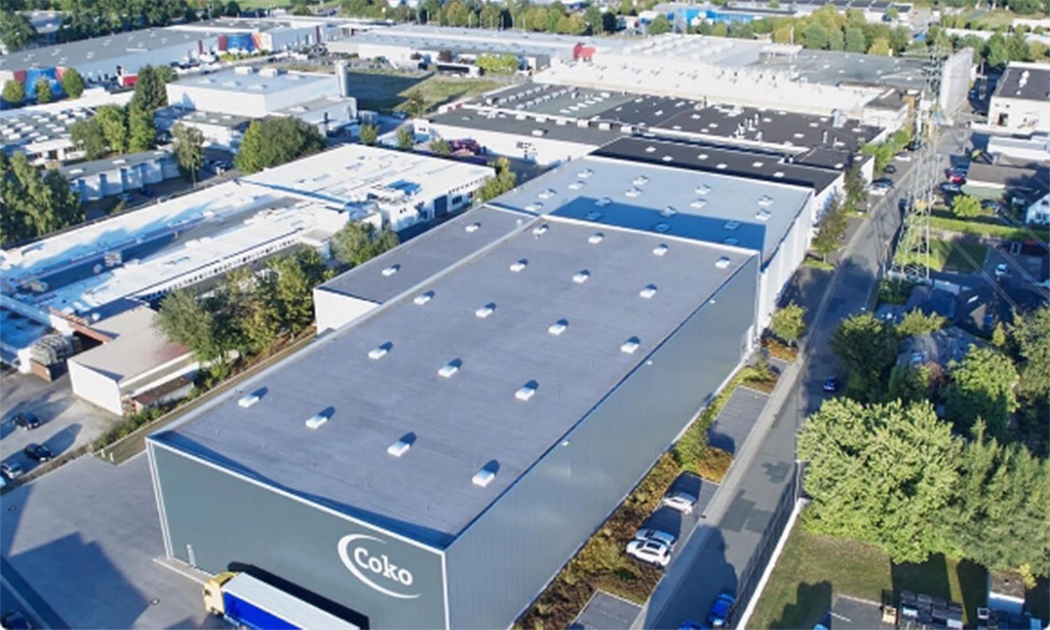 Luftaufnahme des modernen Coko-Werksgeländes mit mehreren Produktions- und Lagerhallen – Kunststofftechnik und Fertigung auf höchstem Industriestandard.