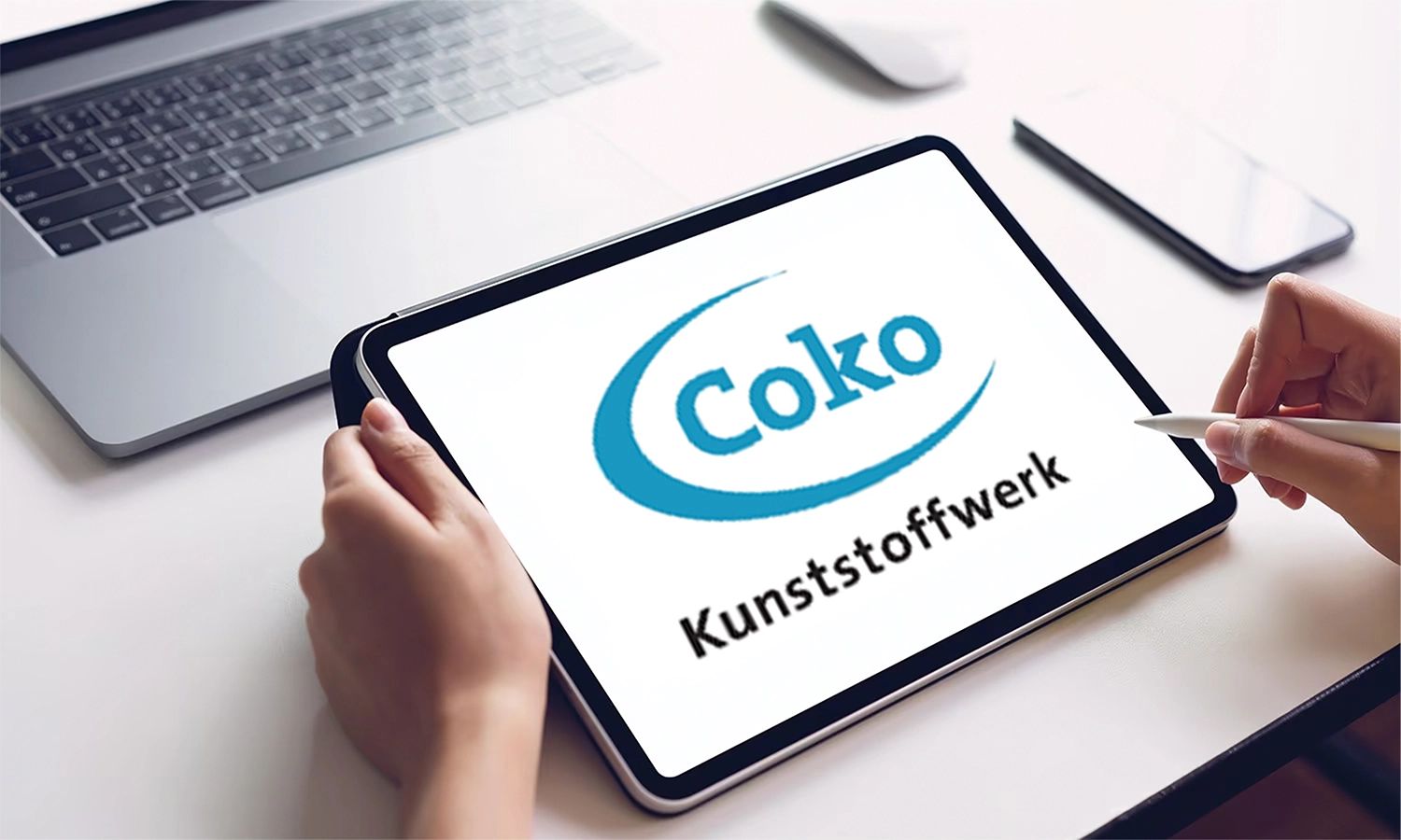 Person arbeitet am Tablet mit dem Coko Kunststoffwerk-Logo auf dem Bildschirm – digitales Arbeiten und Innovation in der Kunststoffverarbeitung.