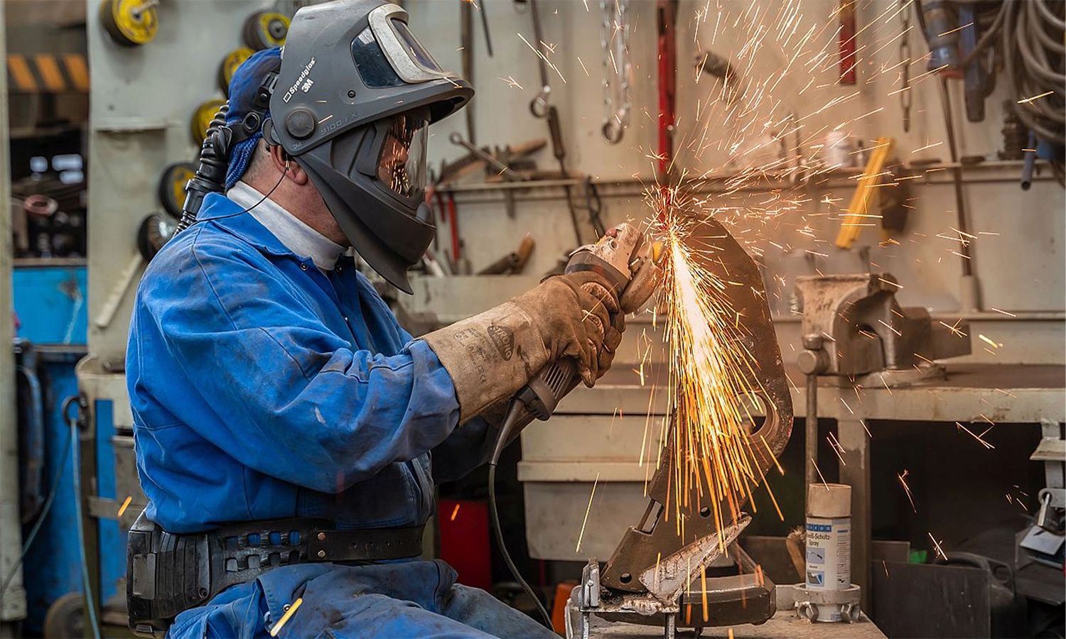 Schweißer der Franz Kaminski Waggonbau GmbH bearbeitet Metallteil mit Winkelschleifer – präzise Handwerksarbeit und Instandhaltung von Eisenbahnkomponenten.