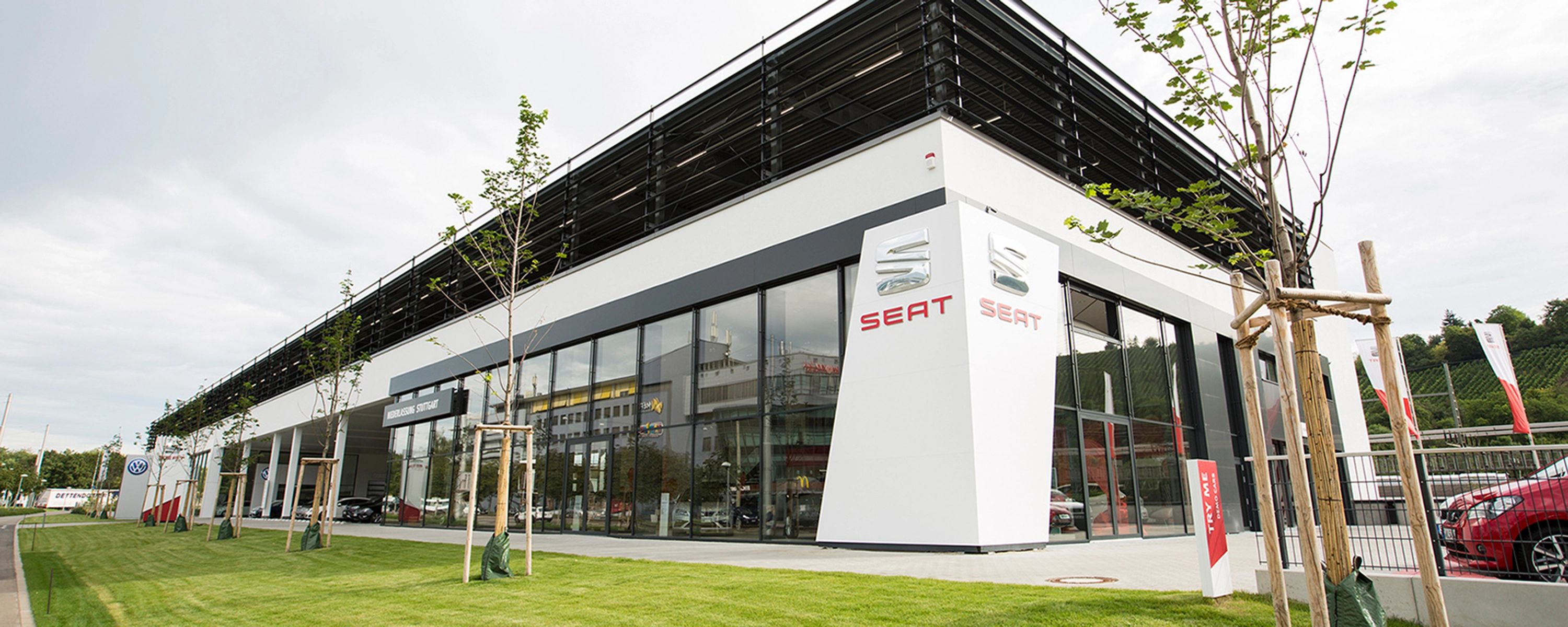 Modernes SEAT‑Autohaus mit Glasfassade und markantem Logo – Außenansicht eines Verkaufs‑ und Servicezentrums der Automarke SEAT.