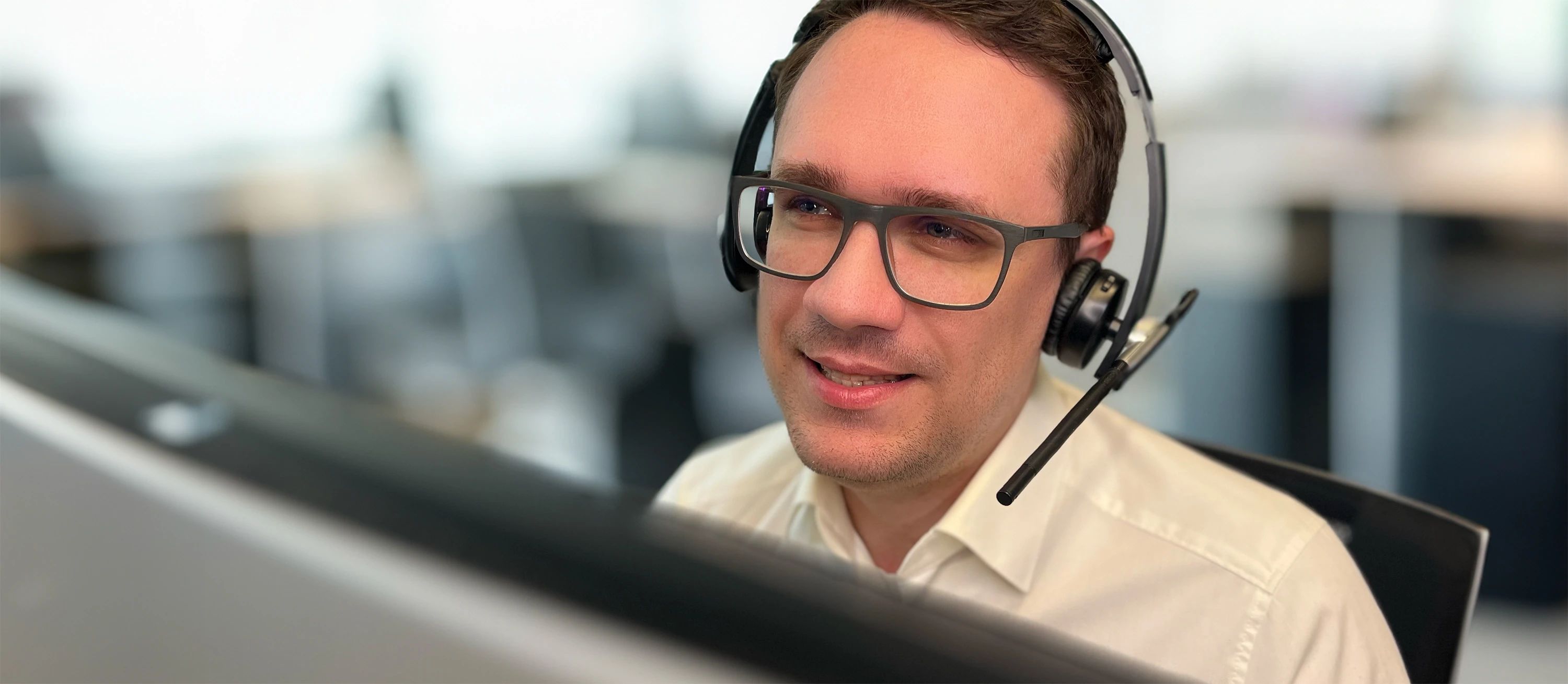 Ein Support-Mitarbeiter mit Headset arbeitet am Computer im Büro.
