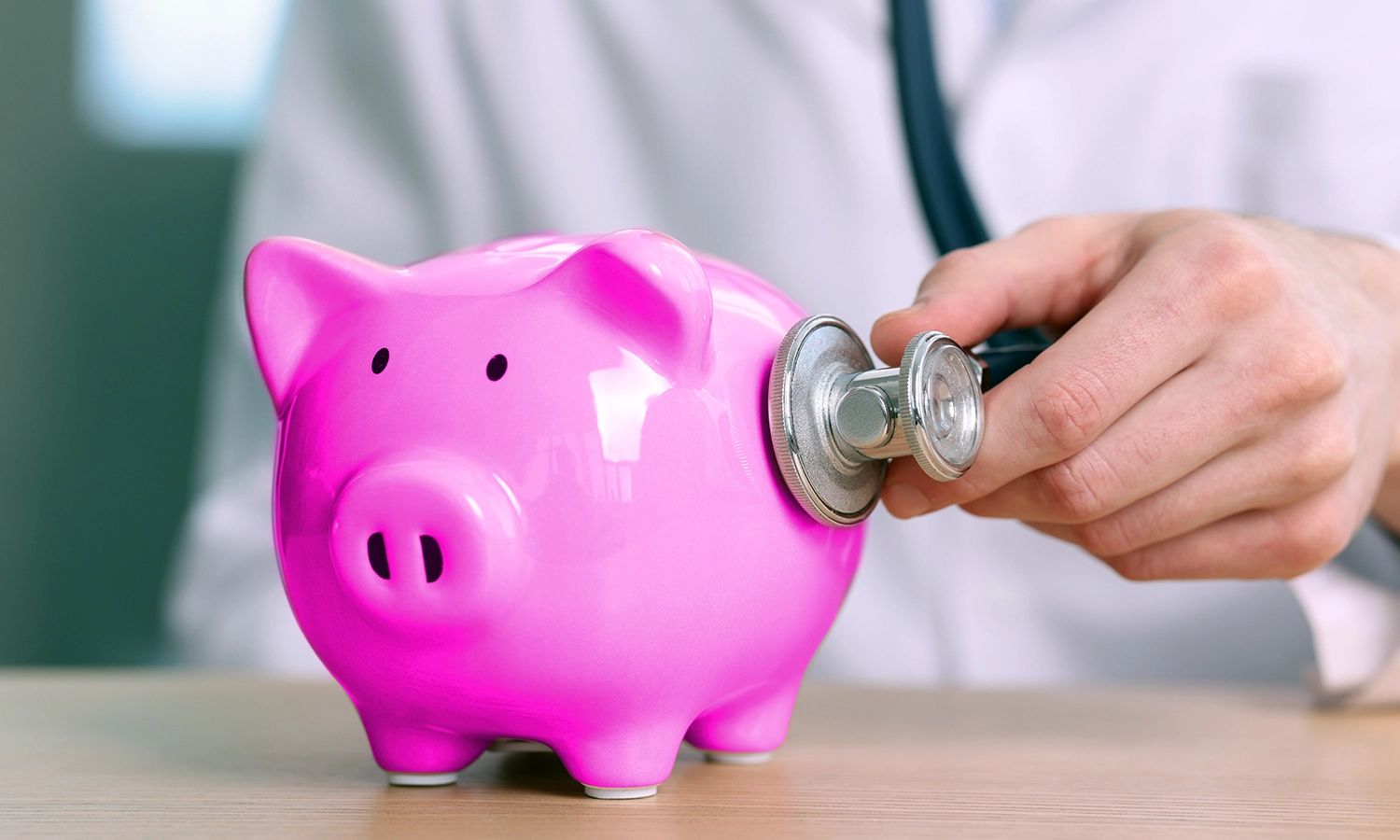 Arzt hört pinkes Sparschwein mit Stetoskop ab