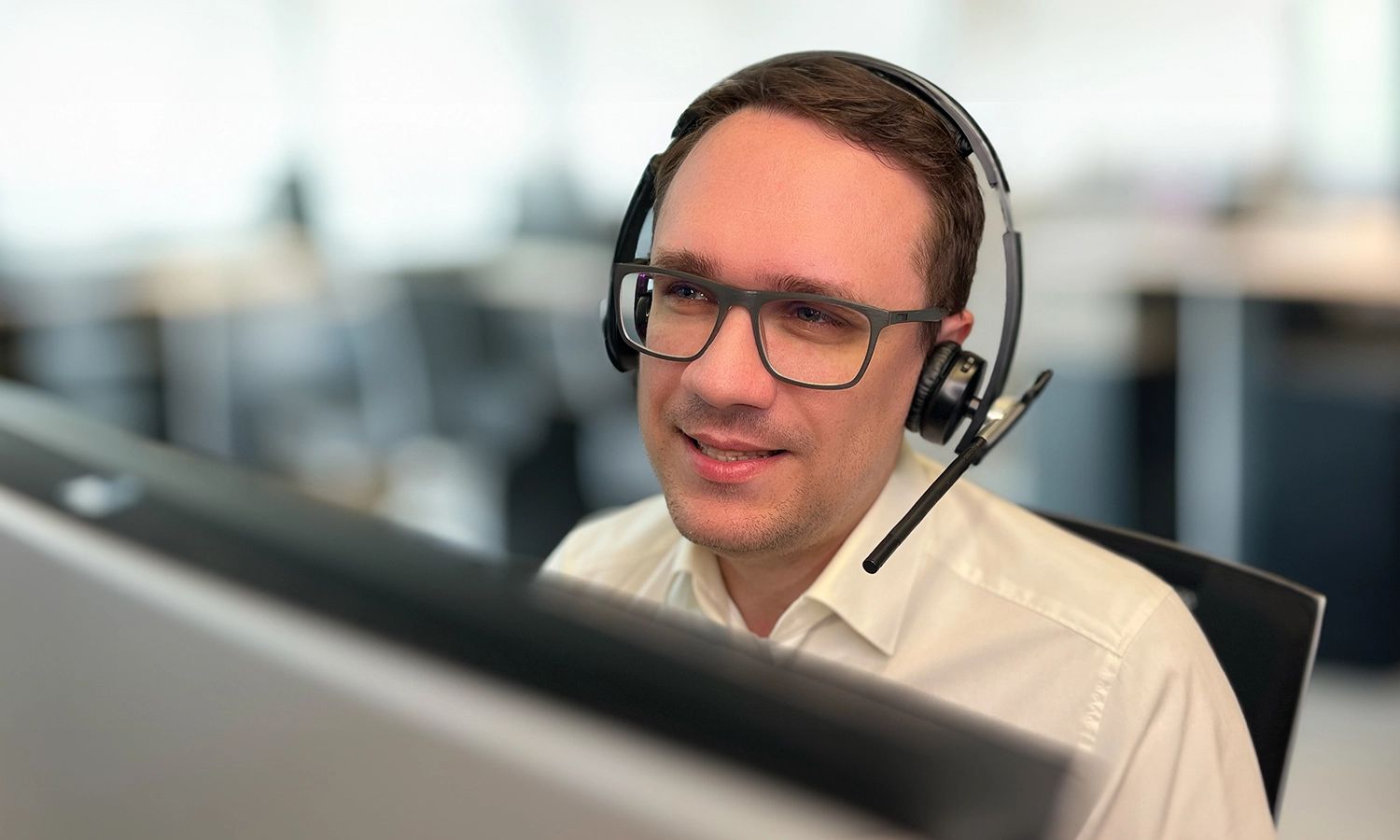 Ein Support-Mitarbeiter mit Headset arbeitet am Computer im Büro.