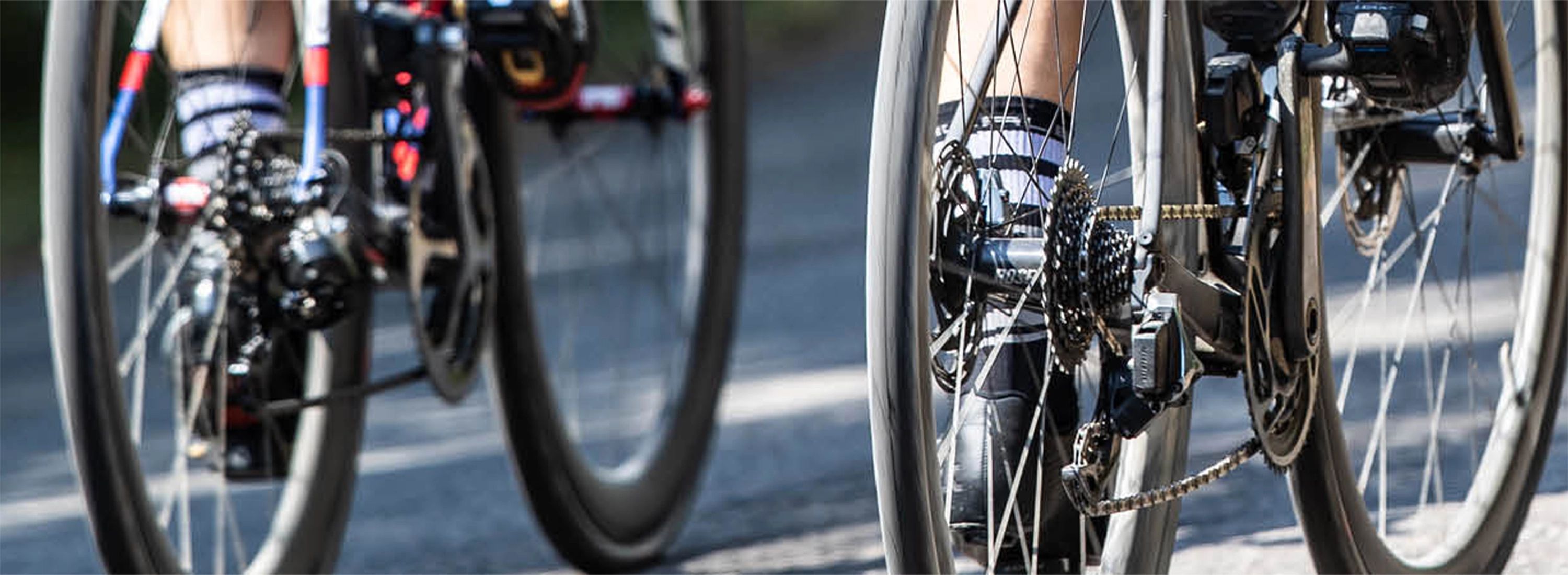 Rennradfahrer unterwegs auf der Straße – Nahaufnahme der Hinterräder mit Schwalbe‑Reifen, Symbol für Performance, Grip und Geschwindigkeit.