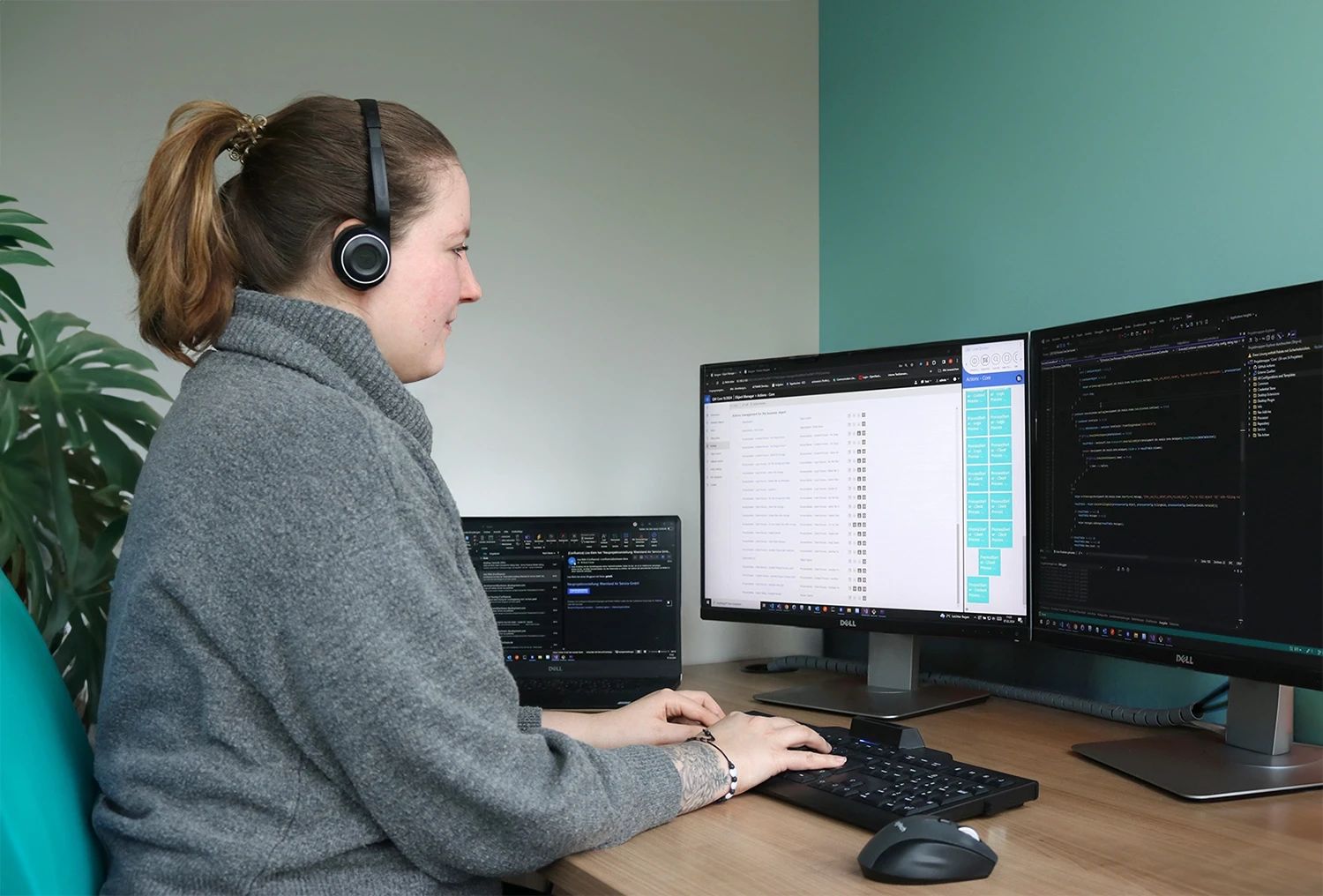Software-Entwicklerin arbeitet an einem Schreibtisch mit zwei Monitoren und Headset.