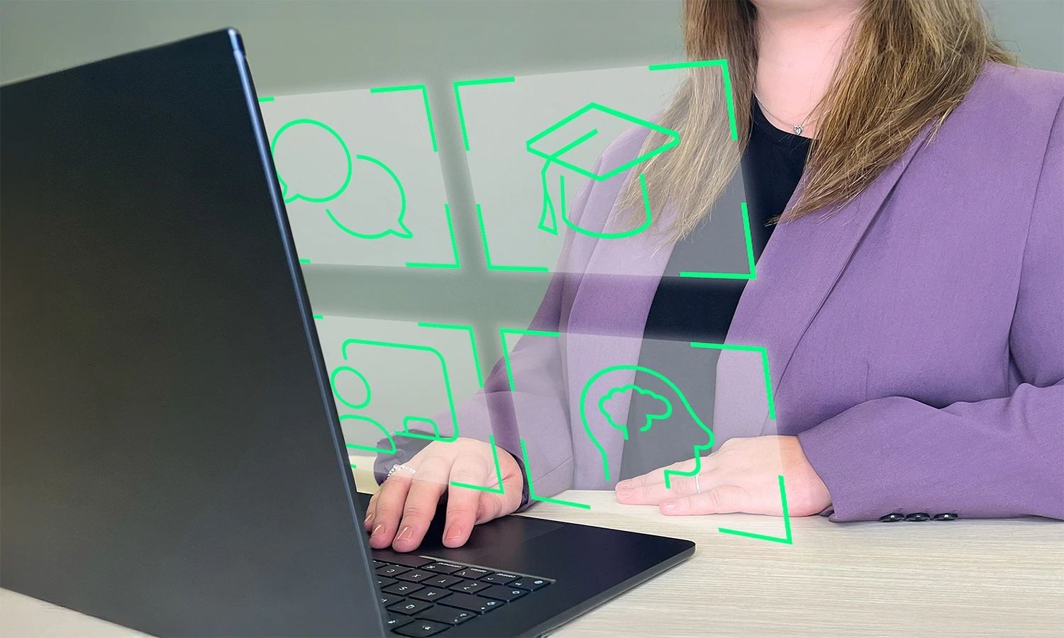 Mitarbeiterin arbeitet an einem Laptop, über dem holografische Icons für E-Learning, Schulung, Kommunikation und Wissen dargestellt sind.