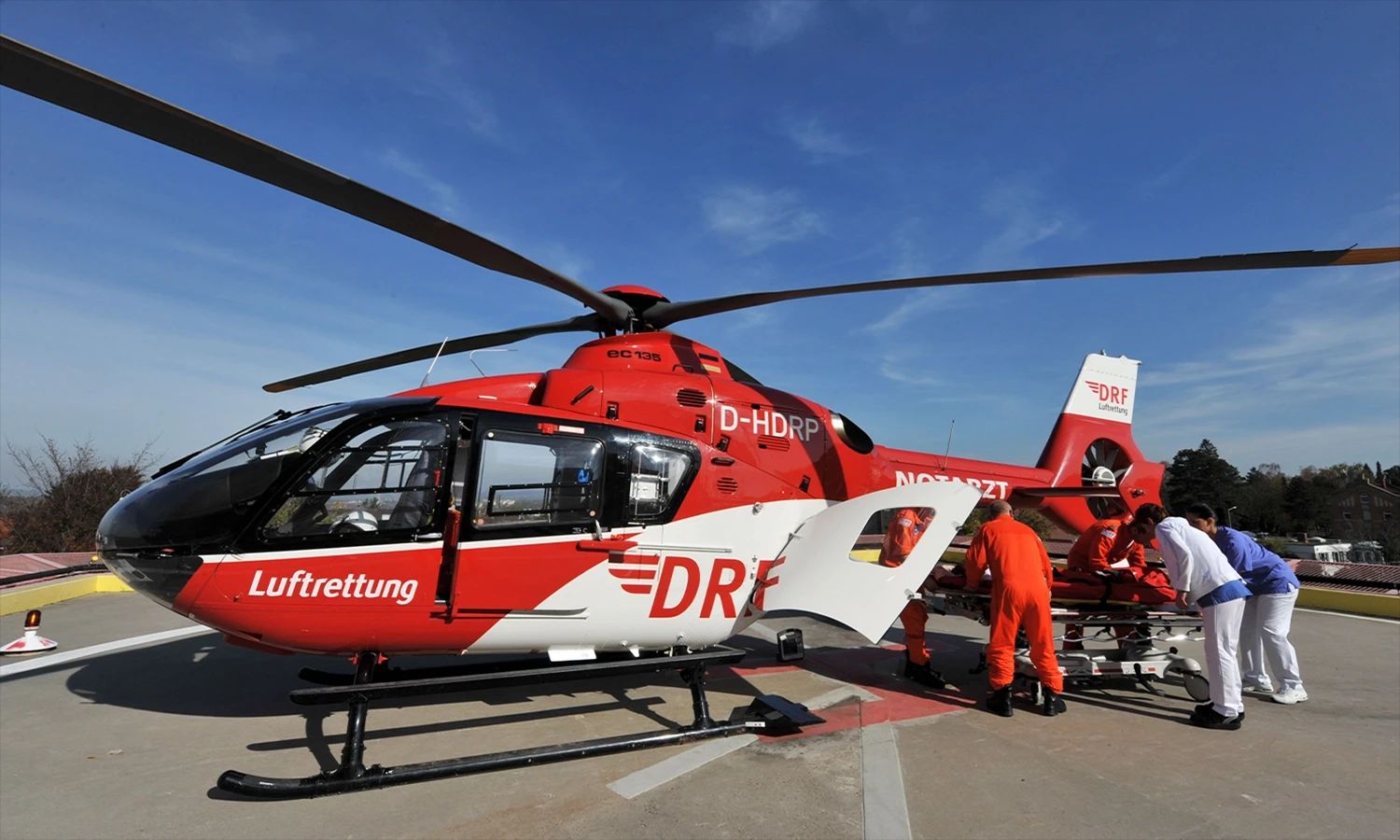 DRF Luftrettungsteam bereitet einen roten Rettungshubschrauber für den Einsatz vor – schnelle medizinische Hilfe und moderne Notfallversorgung aus der Luft.