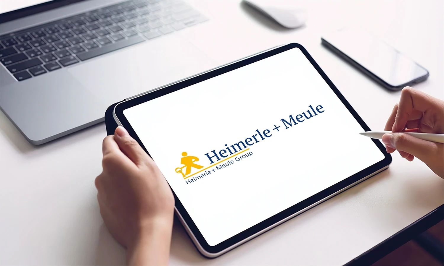 Tablet mit Heimerle + Meule Logo – Darstellung der Marke des traditionsreichen Edelmetallunternehmens für digitale Kommunikation, Innovation und moderne Unternehmensdarstellung.