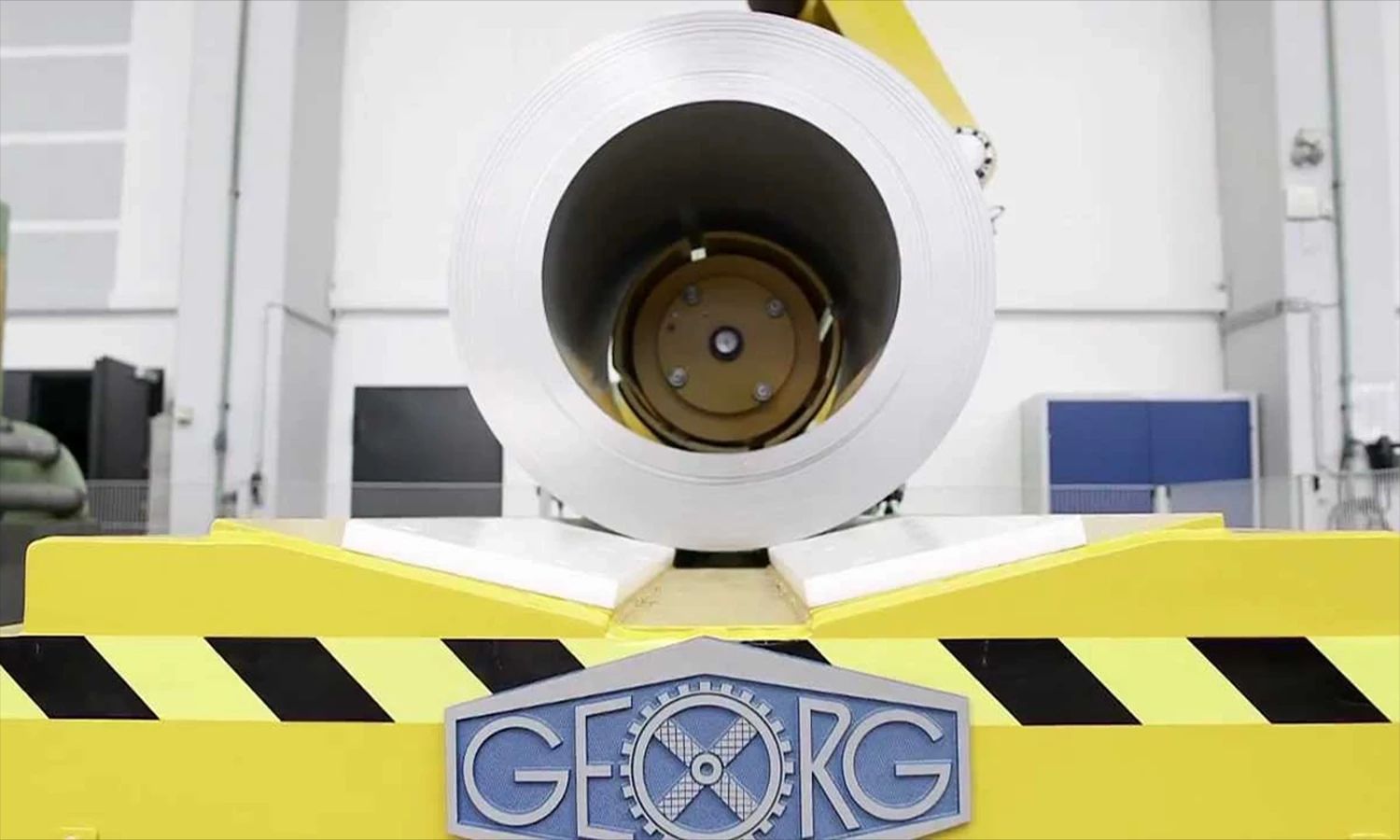 Walzentechnologie von Heinrich Georg – große Metallrolle auf gelber Maschinenvorrichtung mit Firmenlogo, Symbol für Präzision, Engineering und industrielle Fertigungskompetenz.