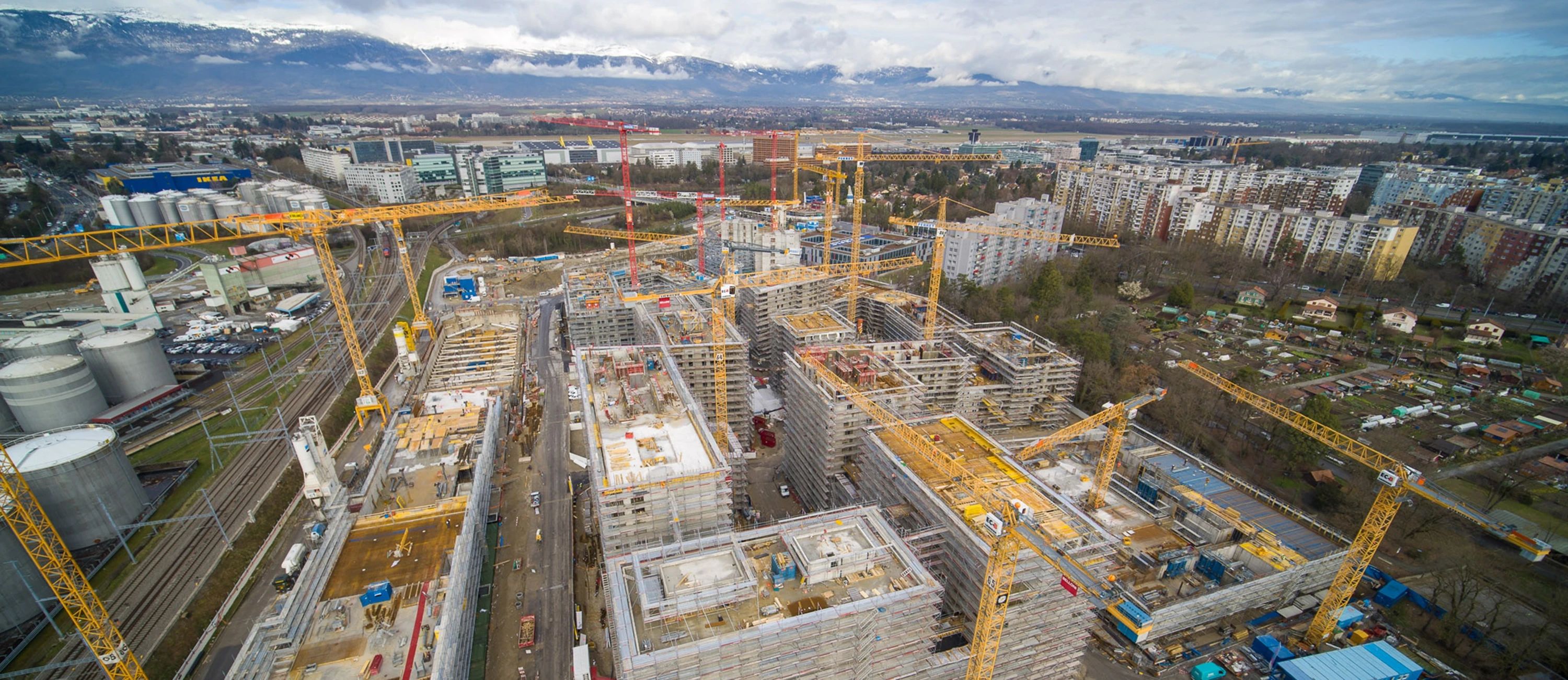 Großbaustelle mit mehreren Kränen und Gebäudekomplexen – Luftaufnahme eines urbanen Bauprojekts mit Gebäudetechniklösungen von Roth.